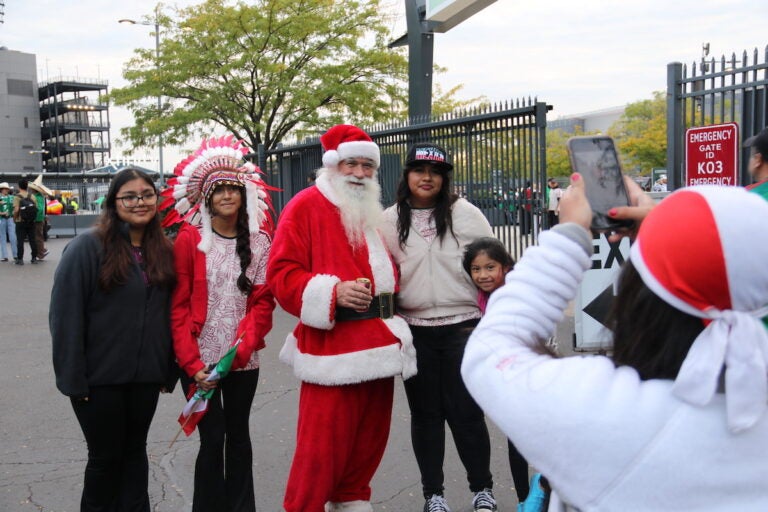 Mexican national soccer team fans pose for a photo with a person in a Santa Claus outfit