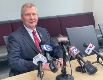 Richard Englert sitting a table in front of several microphones