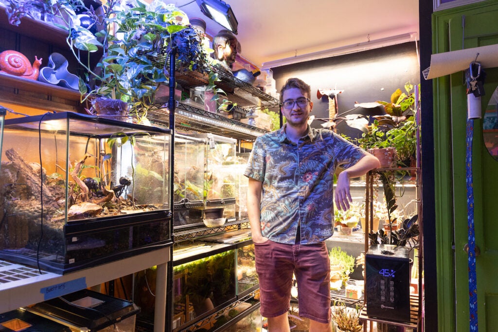 Nick Clark poses for a photo with his plant, amphibian, and insect collection at his home.