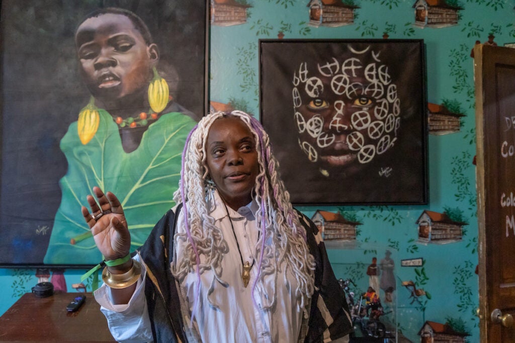 Vashti Dubois stands in front of a painting and other artwork on display.