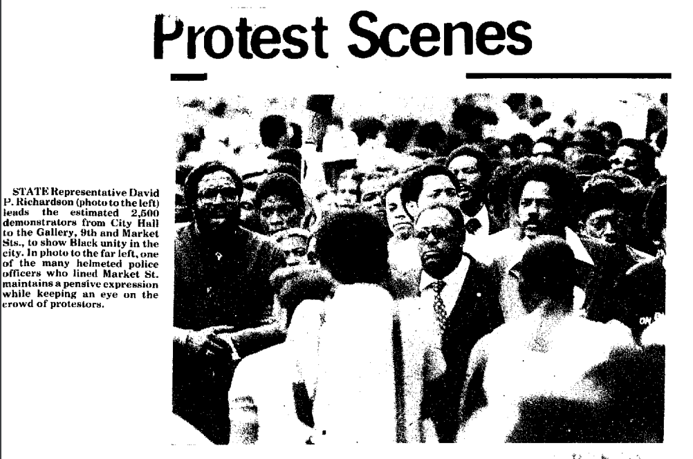 A newspaper clipping reads "Protest Scenes" and shows a black-and-white photo of protesters