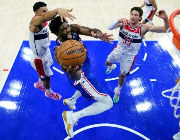 Philadelphia 76ers' Joel Embiid (center) goes up for a shot against Washington Wizards' Johnny Davis, left, and Mike Muscala during the second half of an NBA basketball game, Monday, Nov. 6, 2023, in Philadelphia. (AP Photo/Matt Slocum)