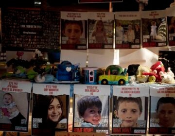 Posters of children held hostage by Hamas in the Gaza Strip are displayed with toys