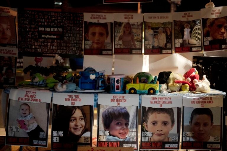 Posters of children held hostage by Hamas in the Gaza Strip are displayed with toys