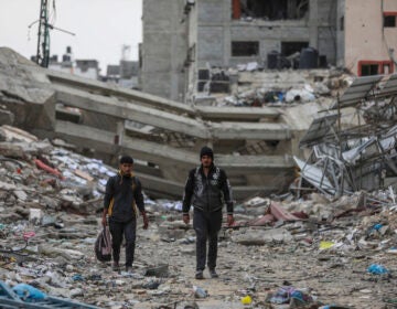 Palestinians walk through destruction in Shati refugee camp