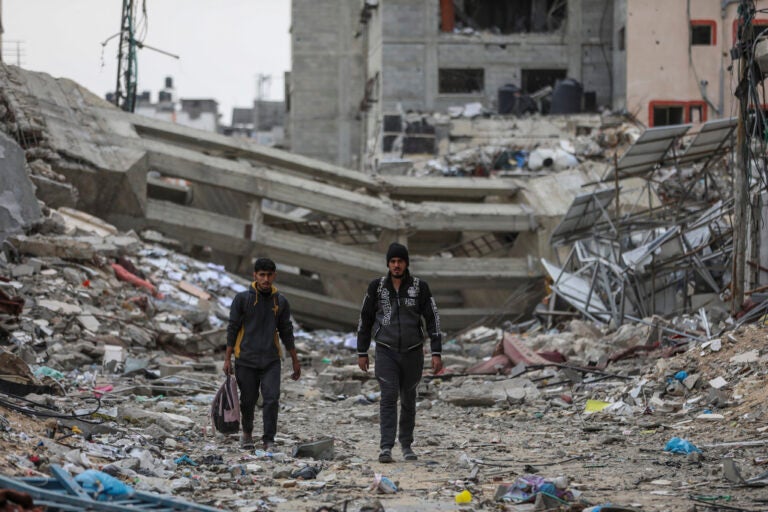 Palestinians walk through destruction in Shati refugee camp