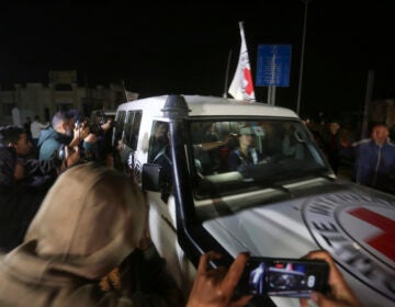 A Red Cross vehicle passes through a crowd of people.