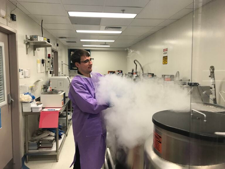 A lab technician opens a freezer