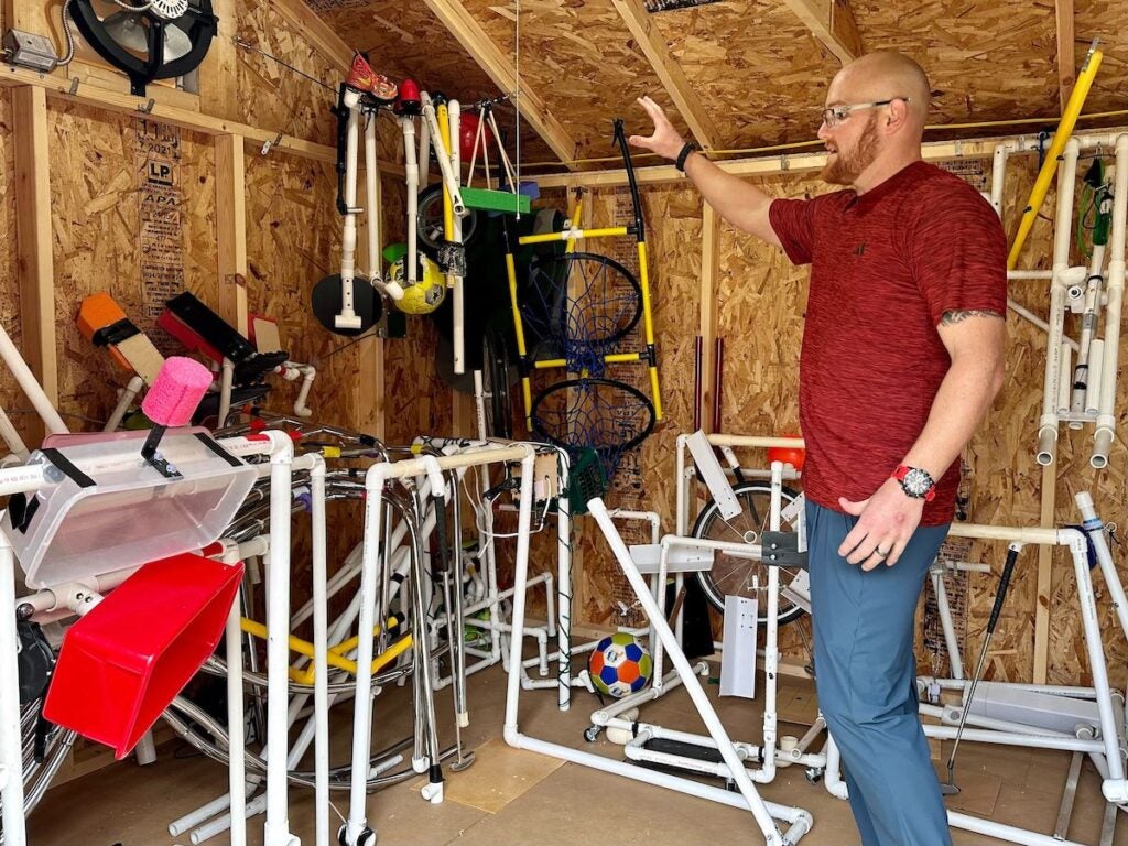 Frank Hughes points at equipment in his shed