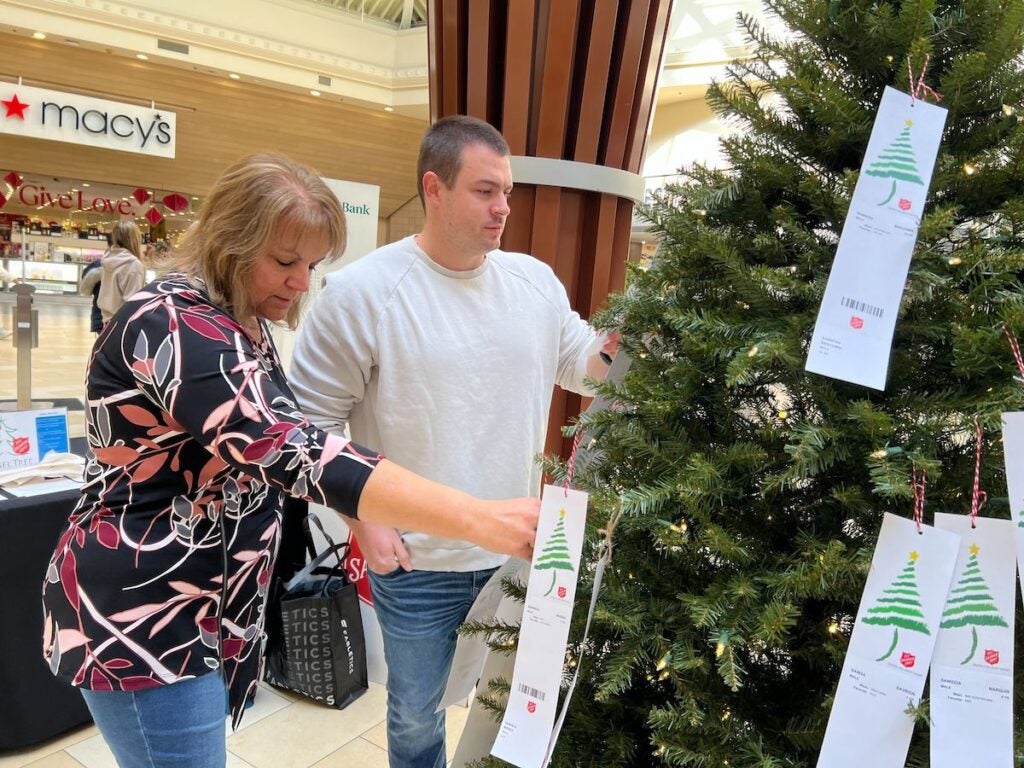 Ryan Barlow and his mother Deb Quinn look at slips of paper hung on a Christmas tree at the mall.