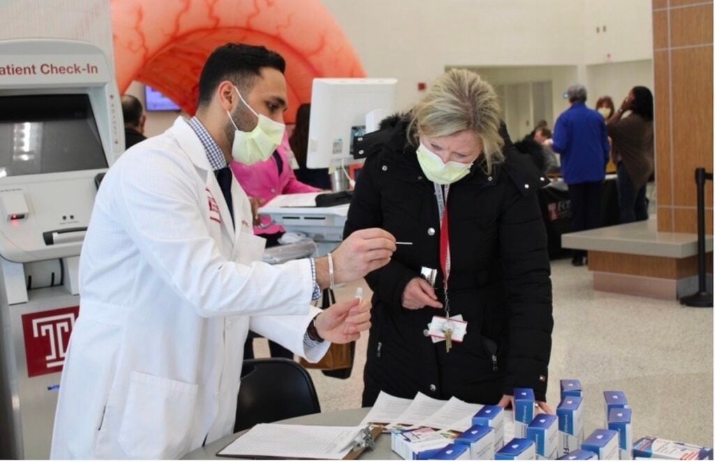 Dr. Rishabh Khatri (left), chief resident in the department of internal medicine at Temple University Hospital, shows someone how a FIT screening kit works.