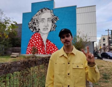 Conrad Benner stands in front of a mural in Fishtown