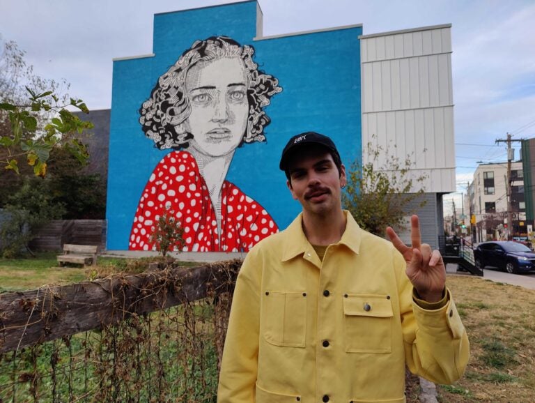 Conrad Benner stands in front of a mural in Fishtown