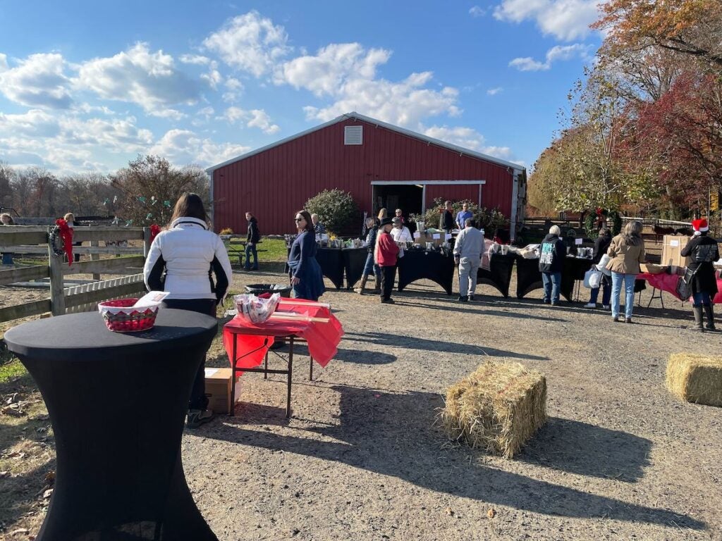 People stand in an open space near a barn