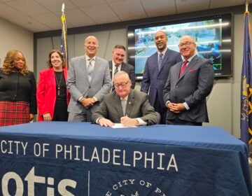 Mayor Kenney sigining a bill with other officials surrounding him.