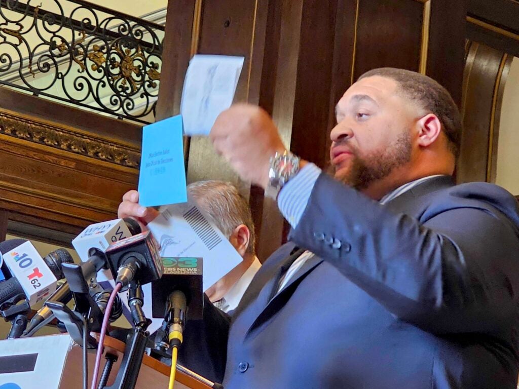 Omar Sabir holding up a mail-in ballot