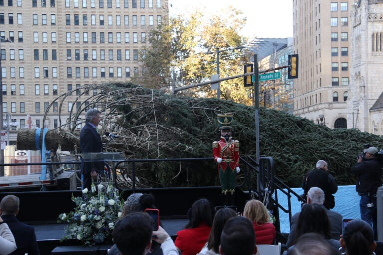 A tree is visible laid on its side in front of a crowd of people outside.