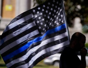 A person carries a flag with a thin blue line, also known as a 