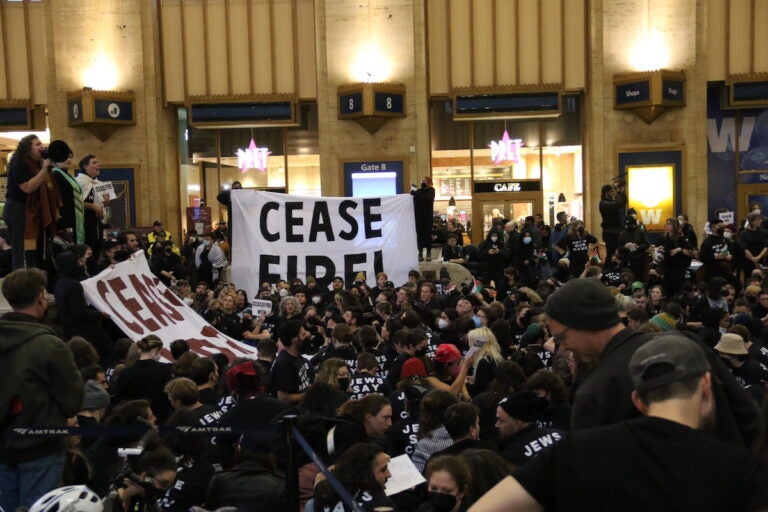Hundreds of people gathered in Philadelphia 30th Street Station's main terminal hold a sign that reads Ceasefire!
