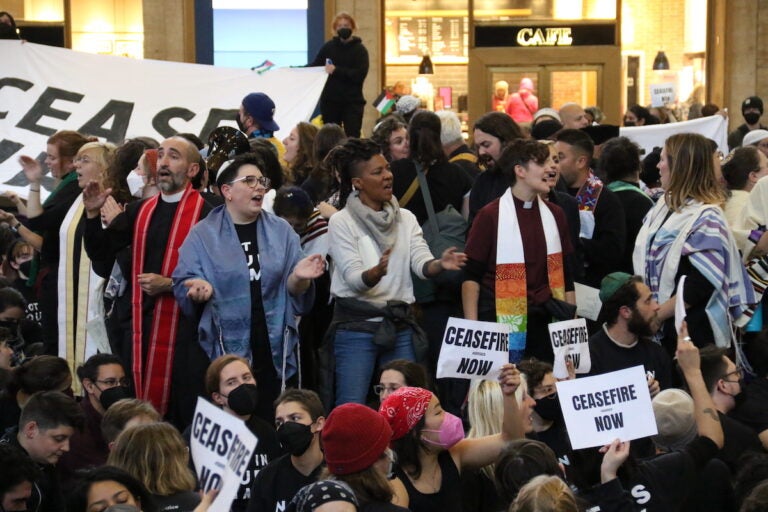 Protesters hold signs that read Ceasefire now.