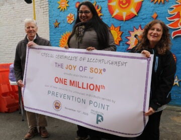 People hold up a sign that reads The Joy of Sox One millionth prevention point.