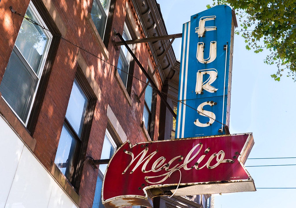 A sign reading Meglio Furs hangs from the side of a building in South Philly