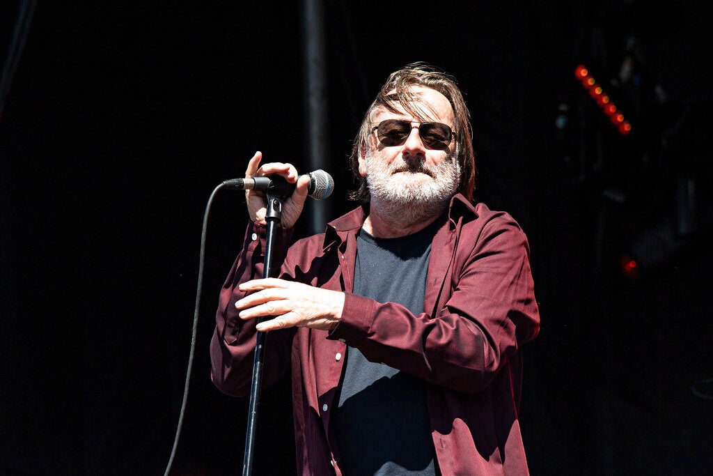 John Lyon of Southside Johnny and the Asbury Jukes performs onstage, singing into a microphone.