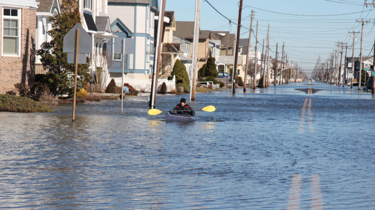 Max Sorensen paddles through his neighborhood in Stone Harbor after flooding