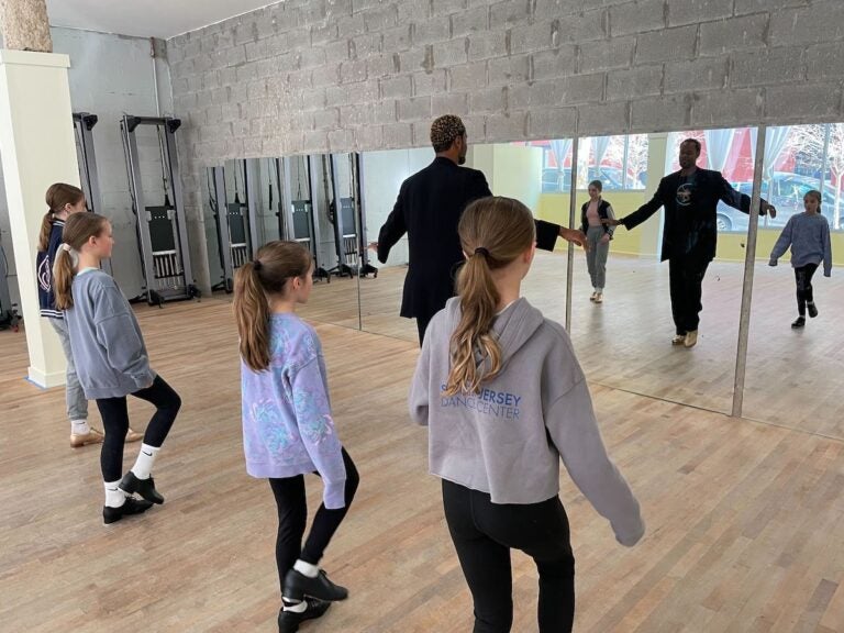 Kids face towards their teachers as the teacher demonstrates a certain tap dance step