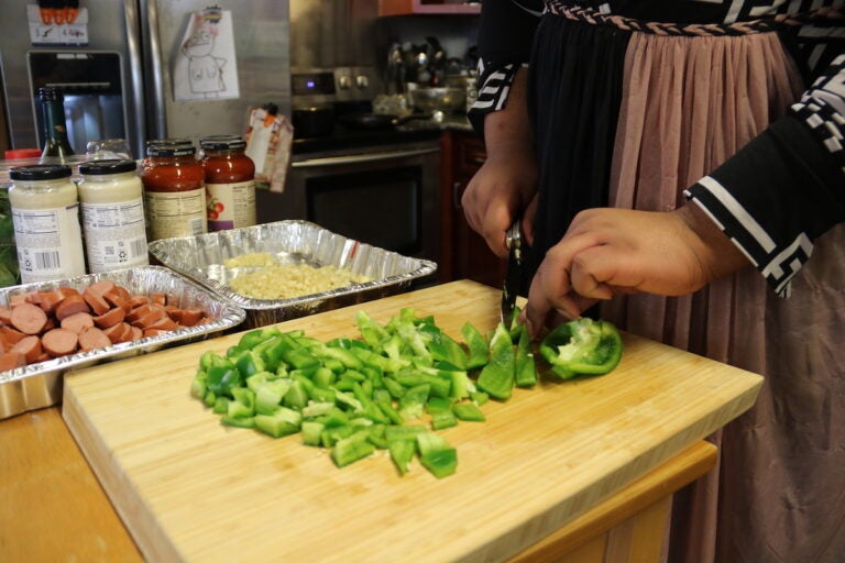 A person chops up green bell pepper