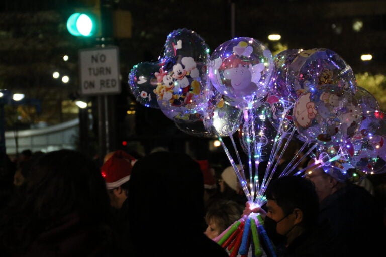 A person holds light up balloons in a crowd