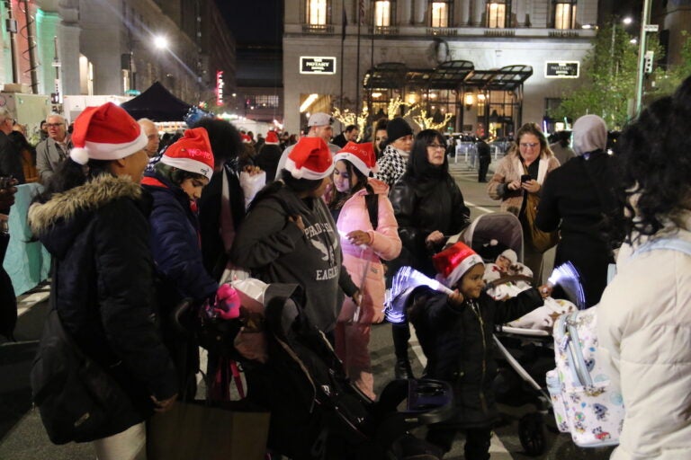 A crowd of people, some of them wearing Santa hats.