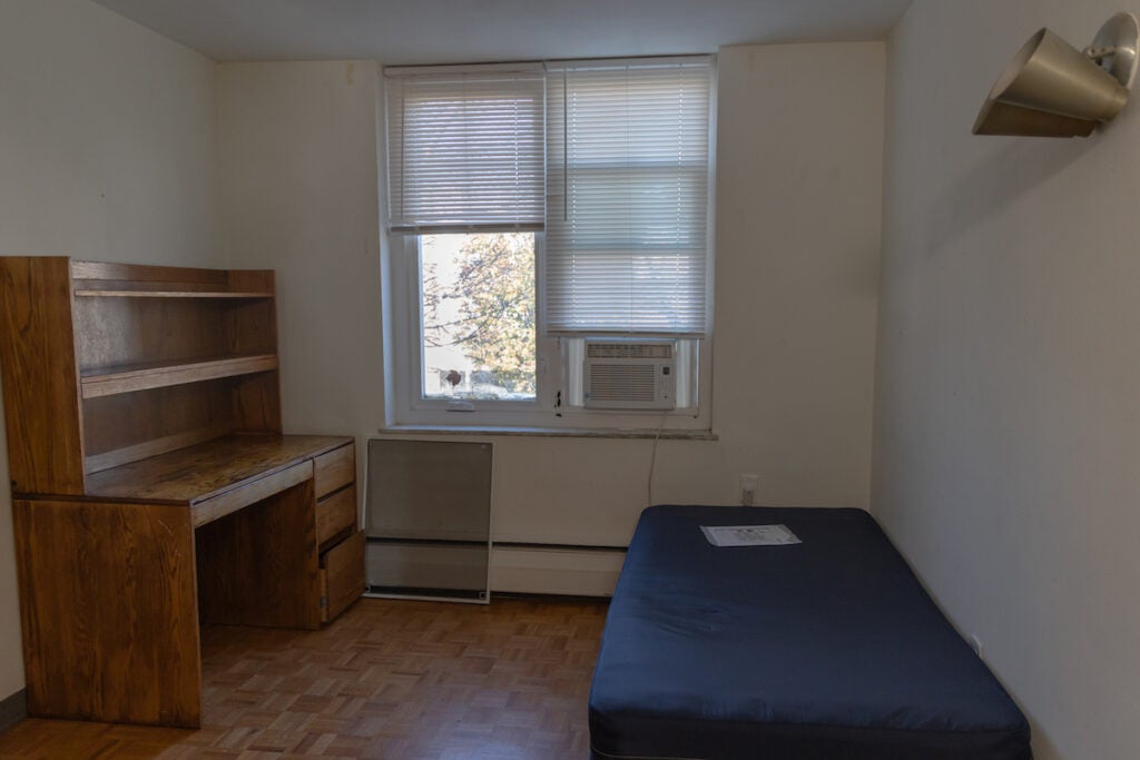 A dorm-style room with a bed and a desk.