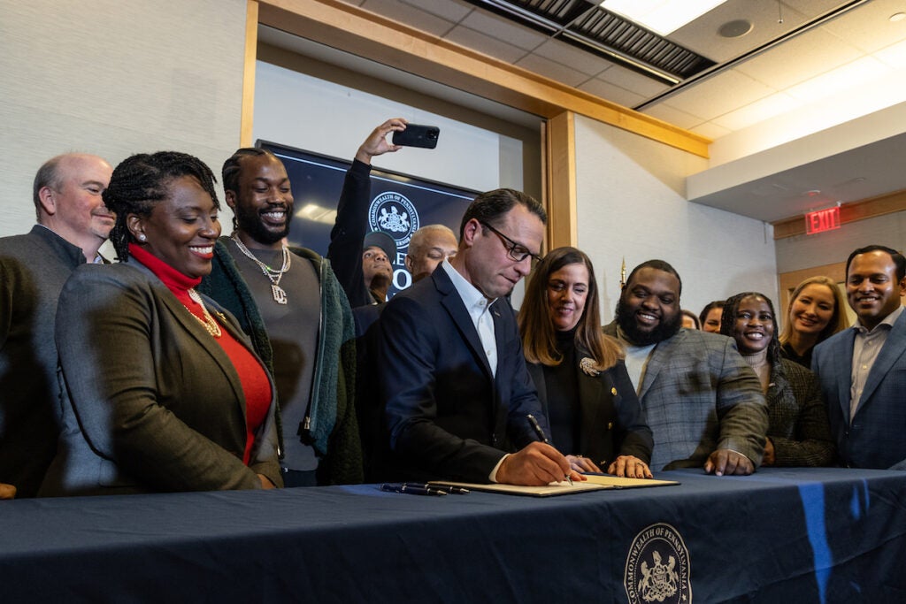 Pa. Governor Josh Shapiro signs a bill as people look on