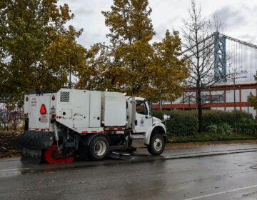 Philadelphia street sweeping vehicles worked to clear debris from Columbus Blvd. after a storm brought heavy rain to the region and the Delaware River overflowed onto the road on December 18, 2023. (Kimberly Paynter/WHYY)