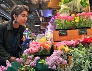At Market Blooms in Reading Terminal Market Anndee Hochman attempts to smell the aromas of lilac and eucalyptus. (Emma Lee/for NewsWorks)