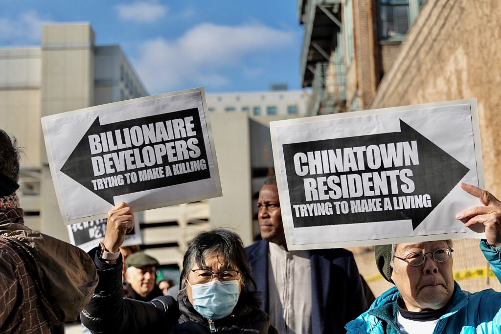 People holding up signs protesting the potential new arena for the Sixers in Chinatown.