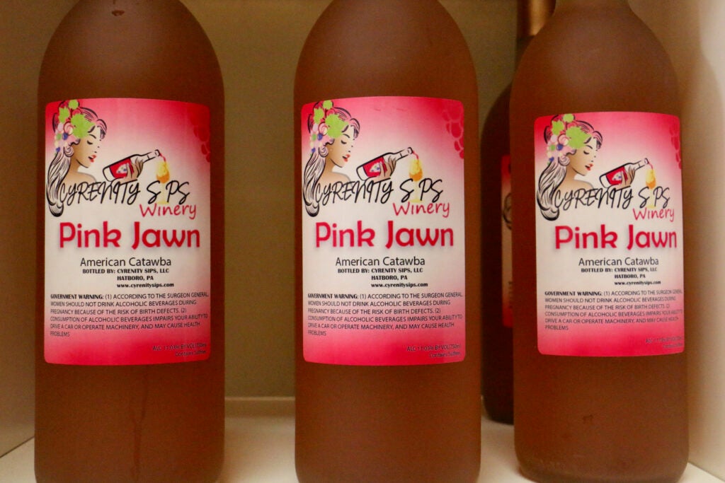 A bottle of wine has the label "Cyrenity Sips Winery, Pink Jawn"