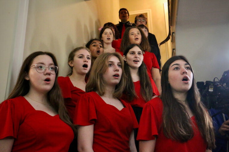 Choir members in red dresses sing