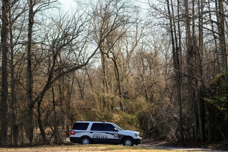 A police vehicle is parked on a road leading to the scene of a helicopter crash in Washington Township