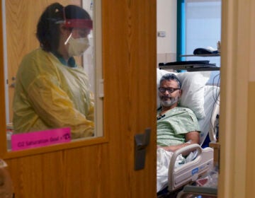 A nurse departs the room of a COVID-19 patient