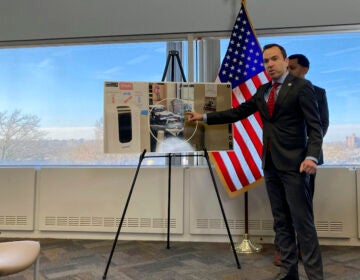 New Jersey Attorney General Matt Platkin points to a photo he says shows guns stored near a ground-floor window at a gun shop, contrary to state law, on Tuesday, Dec. 12, 2023, in Trenton, N.J. The shop was one of three gun dealers Platkin sued on Tuesday. The suits were the first brought by his office under a 2022 law aimed at holding gun dealers accountable by allowing the attorney general to sue under New Jersey's public nuisance laws. (AP Photo/Mike Catalini)