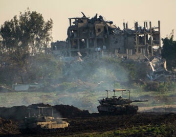 Israeli tanks are seen next to a destroyed building during a ground operation in the northern Gaza Strip, Friday, Dec. 15, 2023. The army is battling Palestinian militants across Gaza in the war ignited by Hamas' Oct. 7 attack on Israel. (AP Photo/Ariel Schalit)