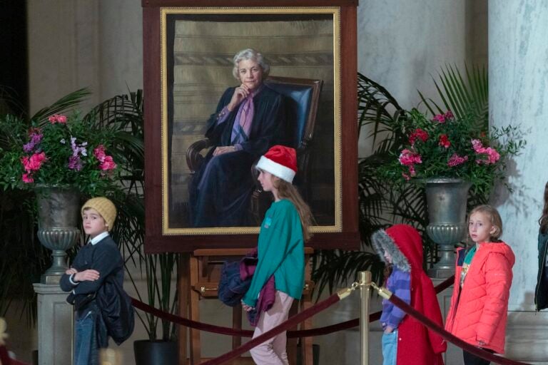 Children pass by the portait of Sandra Day O'Connor as mourners pay their respects as the flag-draped casket of retired Supreme Court Justice Sandra Day O'Connor lies in the Great Hall at the Supreme Court in Washington, Monday, Dec. 18, 2023. O'Connor, an Arizona native and the first woman to serve on the nation's highest court, died Dec. 1 at age 93.