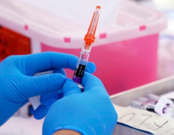 An upclose view of someone holding a syringe of the flu vaccine