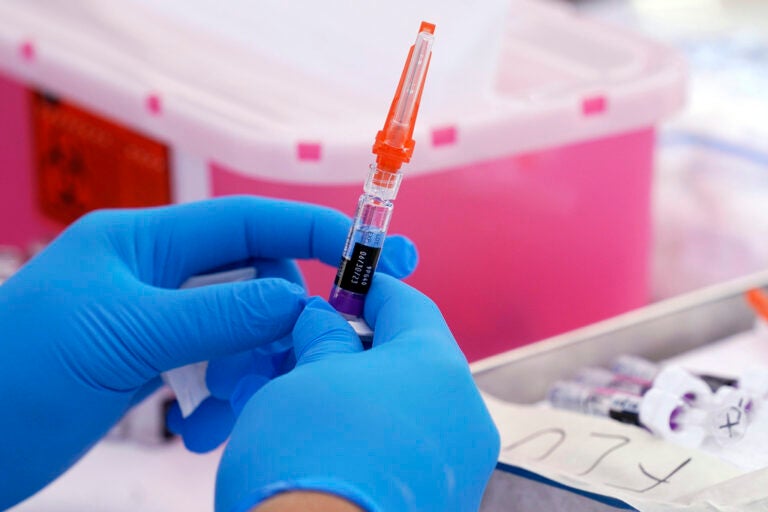 An upclose view of someone holding a syringe of the flu vaccine