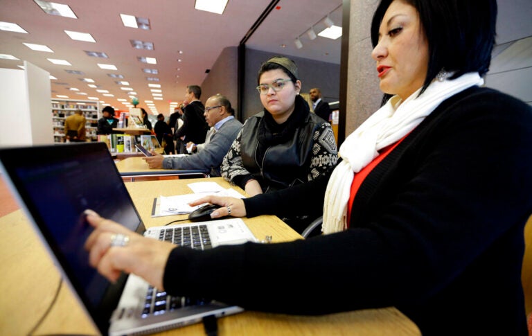 Affordable Care Act health insurance marketplace navigator Leticia Chaw, right, helps gather information for Jennifer Sanchez