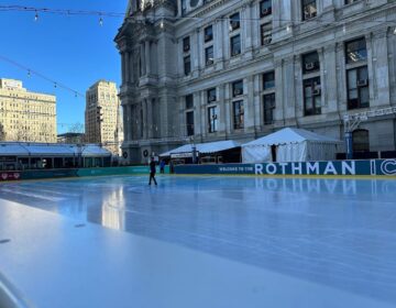 A lone ice skater skates on the rink in front of City Hall