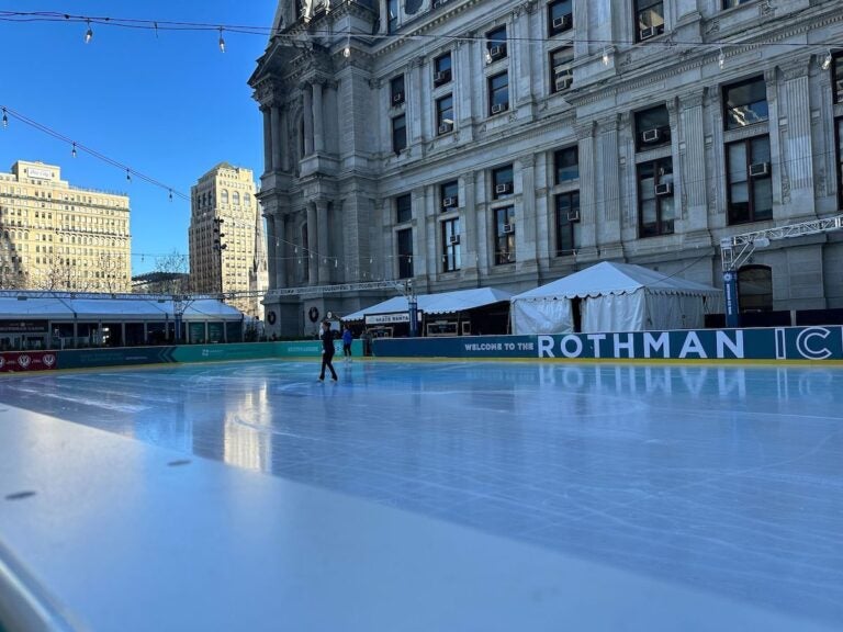 A lone ice skater skates on the rink in front of City Hall