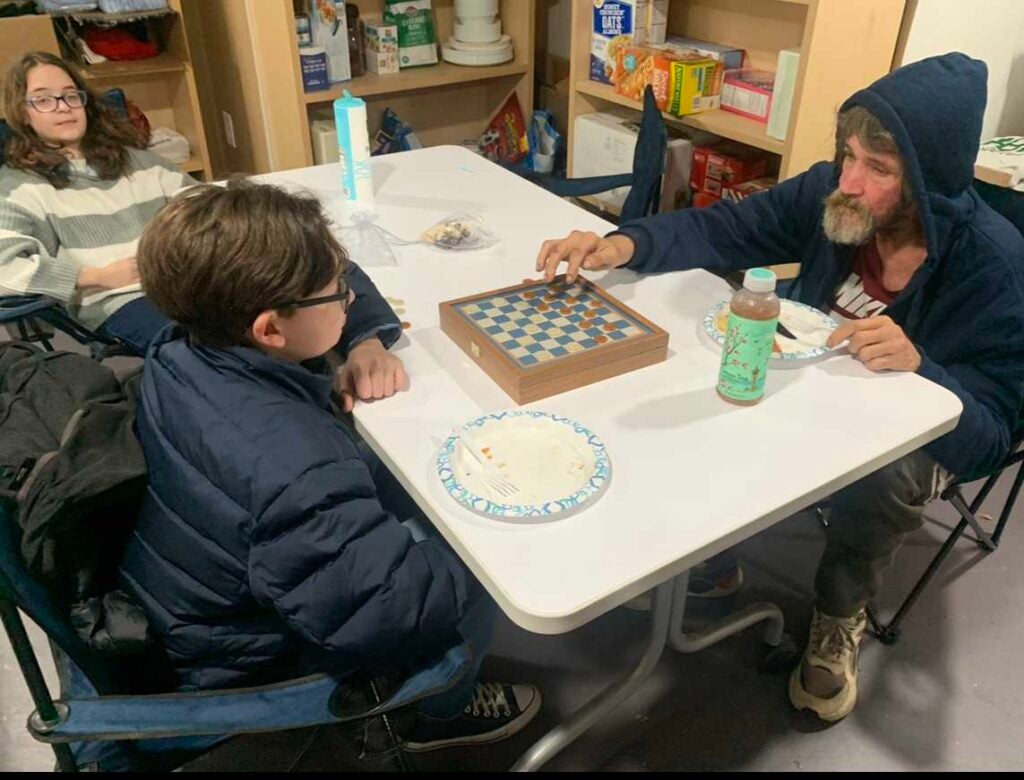 Breaking Bread residents and volunteers play checkers during the shelter's game night